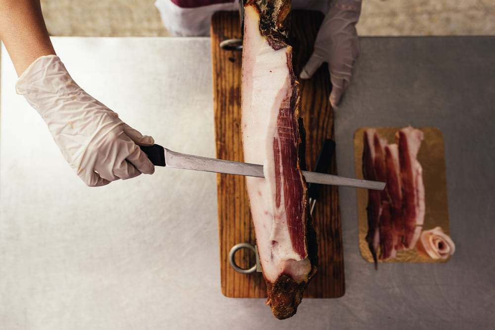 Maestro cortador preparando jamón con cuchillo profesional.